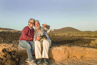 Portrait of smiling senior couple sitting at beach