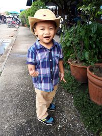 Portrait of cute boy wearing hat standing on footpath
