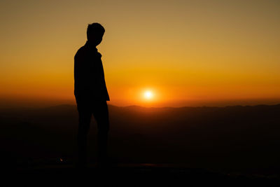 Silhouette man standing against orange sky during sunset