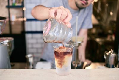 Midsection of male worker making coffee in cafe