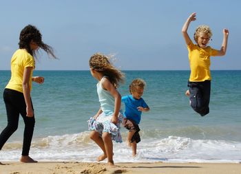 Full length of siblings standing on beach against clear sky