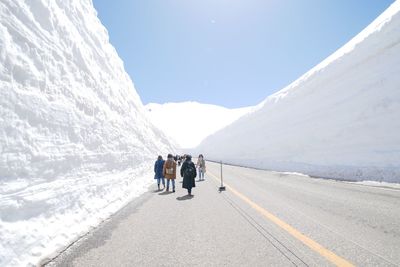 Rear view of people walking on snowcapped mountain road