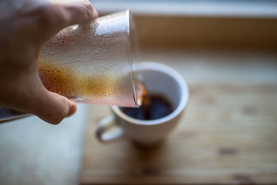 Cropped image of person pouring coffee in cup