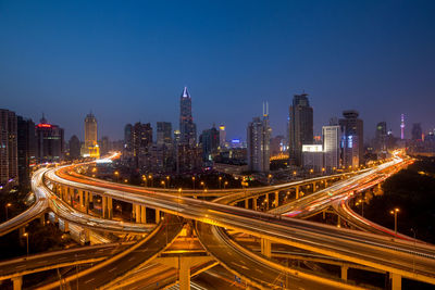 Light trails on elevated road against buildings at night