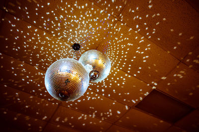 Low angle view of illuminated disco balls hanging from ceiling in nightclub