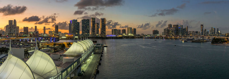 Panoramic view of sea and buildings against sky during sunset