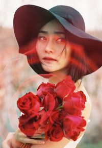 Close-up of thoughtful woman holding red roses