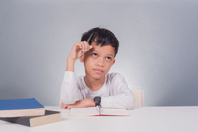 Portrait of boy sitting on table against wall