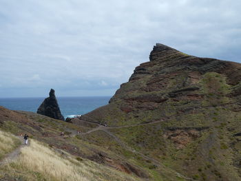 Scenic view of cliff by sea against sky