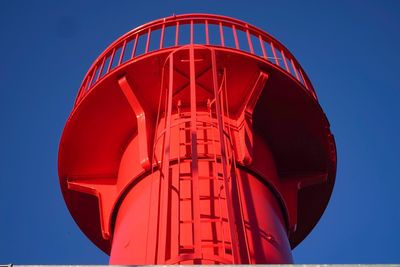 Low angle view of red light against clear blue sky