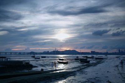 Boats moored in sea against sky during sunset