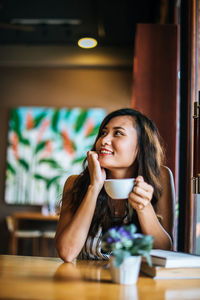 Portrait of a young woman drinking coffee in restaurant