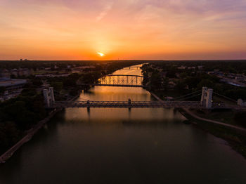 Bridge over river against sky during sunset