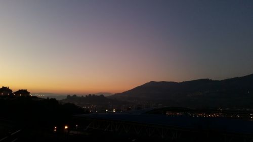 Silhouette town against clear sky at sunset