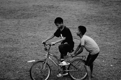 Teenage boys riding bicycle on field