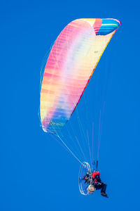 Low angle view of person paragliding against clear blue sky