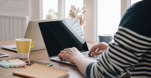 Midsection of woman using smart phone on table