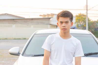 Portrait of young man standing on car