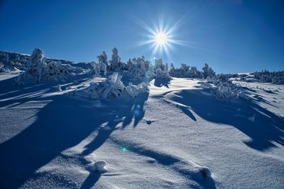 Panoramic view of snow covered land against sky on sunny day