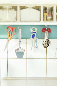 Kitchen equipment hanging on cabinet against tiled wall