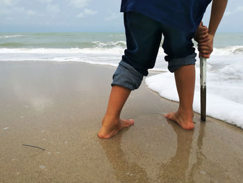 Low section of man standing on beach