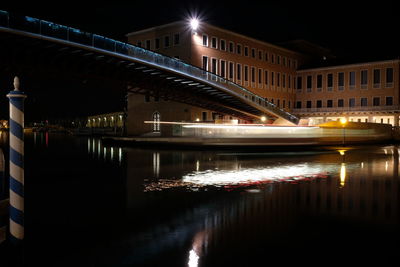 Illuminated bridge over river in city at night