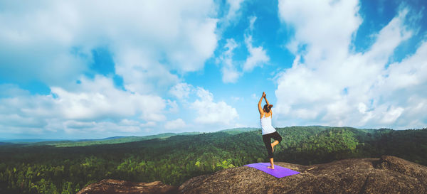 Rear view of woman standing on mountain against sky