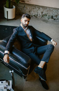 Portrait of young man sitting on sofa at home