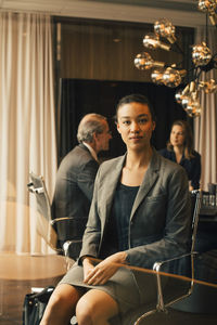 Portrait of confident female advisor with colleagues in background at office