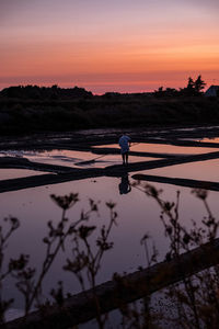 Silhouette man on beach against sky during sunset