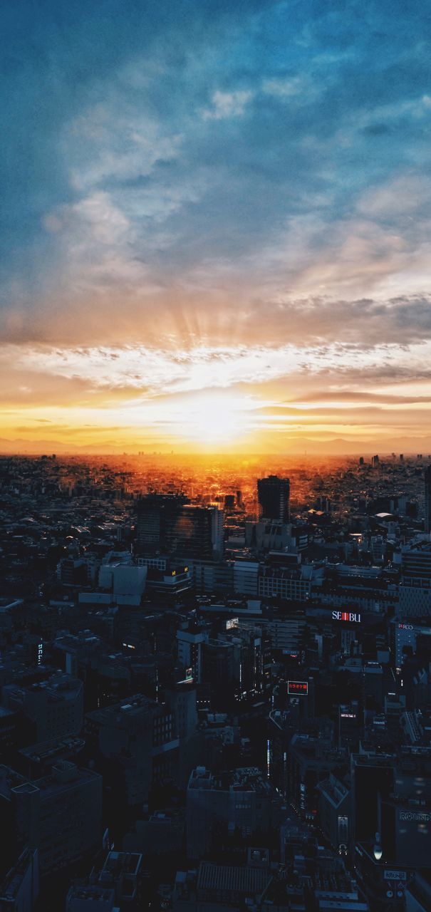 HIGH ANGLE SHOT OF ILLUMINATED CITYSCAPE AGAINST SKY DURING SUNSET