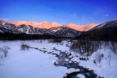 Scenic view of snow covered mountains against blue sky