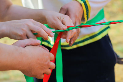 Hands braid green and red ribbons. joint, collective work