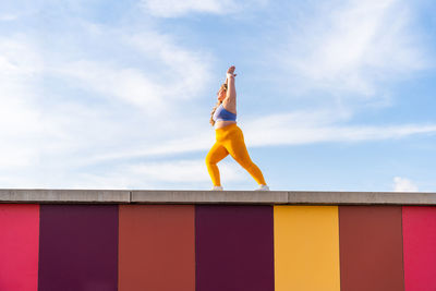 Full length of woman exercising against sky