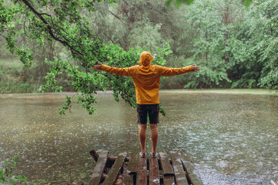 Full length rear view of man standing by lake