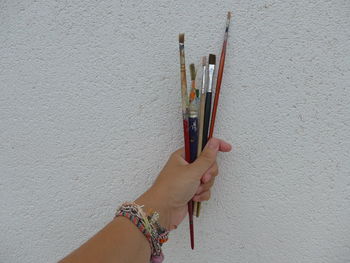 Close-up of hand holding paint against wall