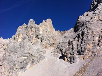 Low angle view of rock formations against clear blue sky