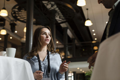 Low angle view of businesswoman gesturing while talking with male delegate at seminar