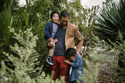 Happy father with sons standing amidst plants in balboa park