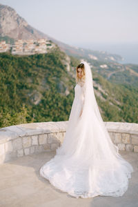 Rear view of woman with arms raised standing against wall