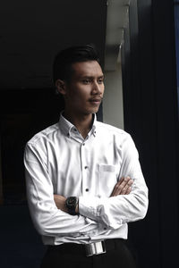 Portrait of young man standing against wall