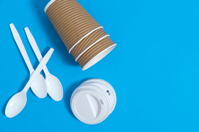 Reusable cups on a blue background with plastic caps and spoons