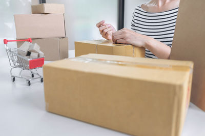 Midsection of woman tying cardboard box