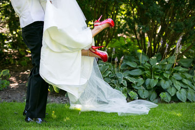 Midsection of woman holding umbrella standing on field