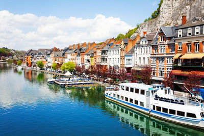 Buildings by river against sky in city