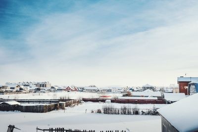 Houses on snow covered field against sky