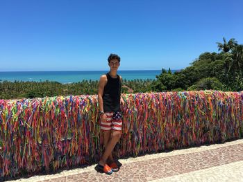 Portrait of boy standing against multi colored ribbons at beach