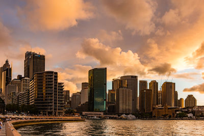 City at waterfront against cloudy sky