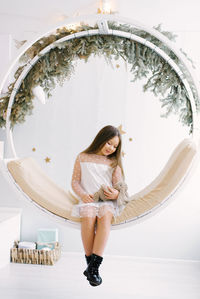 A girl celebrates the new year holding a gift in her hands and sitting on a swing