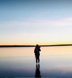 Silhouette of man looking at sea against sky